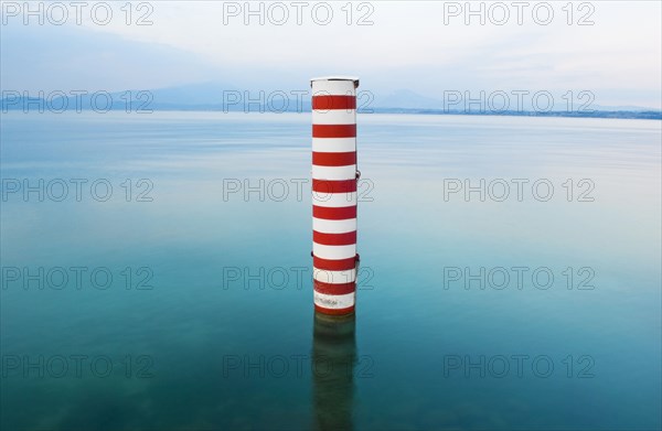 Red and white stripe pillar in tranquil lake