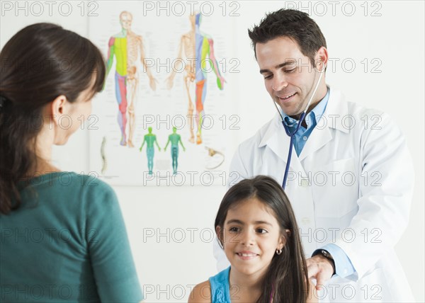 Doctor examining girl as mother watches