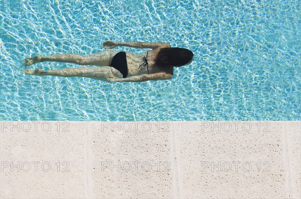 Mixed race woman swimming in pool