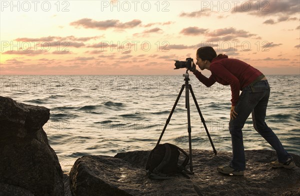 Mixed race woman using camera near ocean