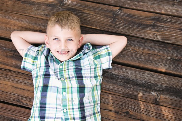 Caucasian boy laying on wooden deck