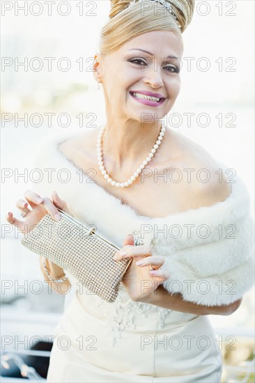 Smiling Hispanic bride holding purse