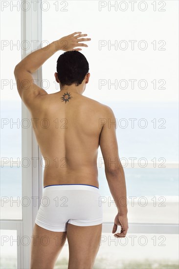 Hispanic man standing at window