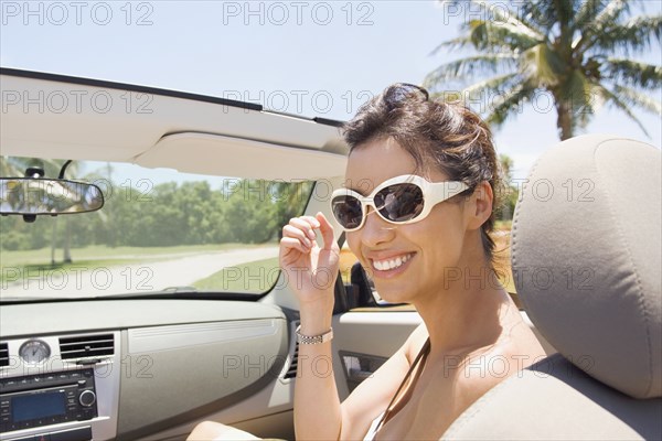 Hispanic woman riding in convertible