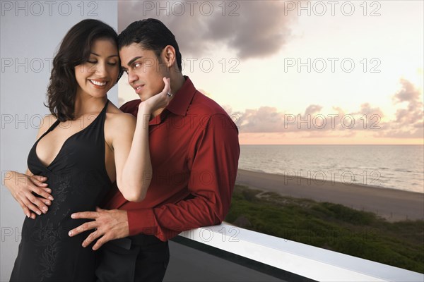 Hispanic couple hugging on balcony