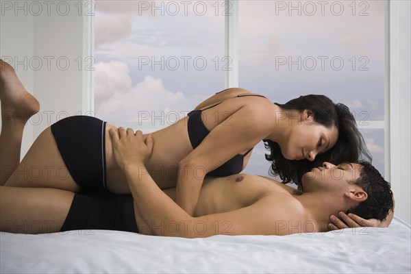 Hispanic couple hugging on bed