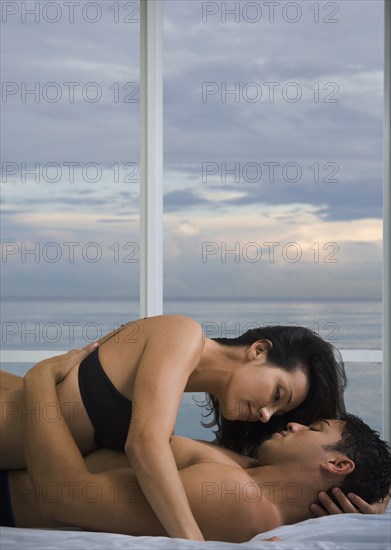 Hispanic couple hugging on bed