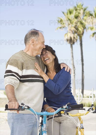 Couple walking bicycles on beach