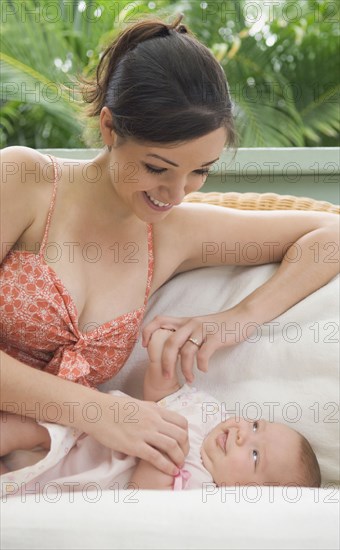 Mother playing with baby on sofa