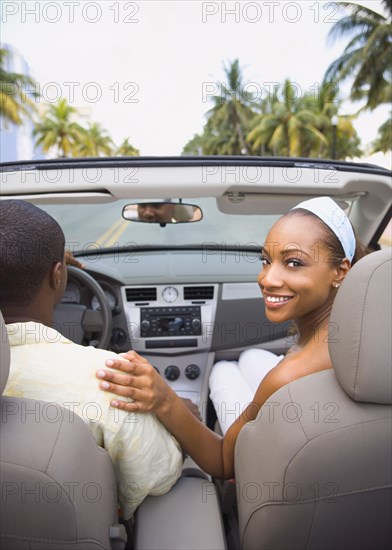 African American couple driving in convertible