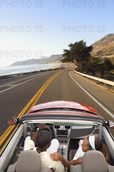 Couple driving convertible on coastal road
