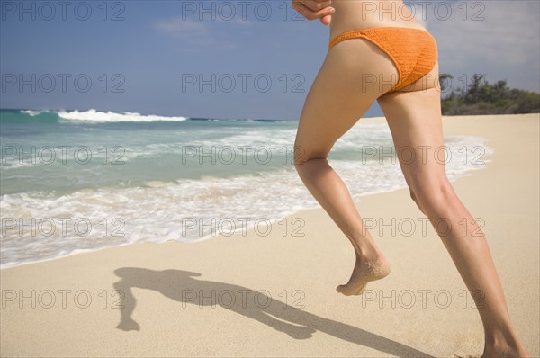 Caucasian woman running in bikini on beach