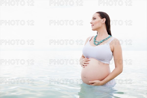 Pregnant Caucasian woman standing in water