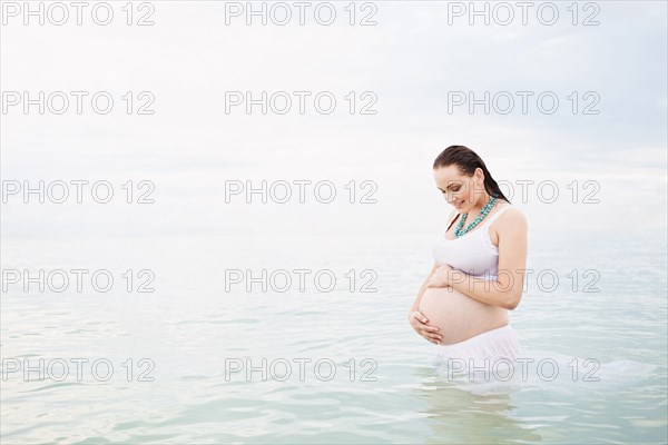 Pregnant Caucasian woman standing in water