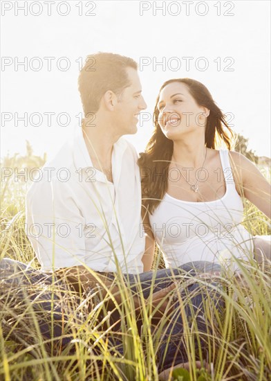 Caucasian couple sitting in tall grass