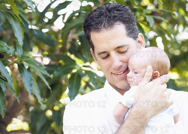 Caucasian father holding baby outdoors