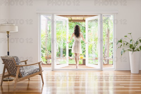 Hispanic woman opening French doors to patio