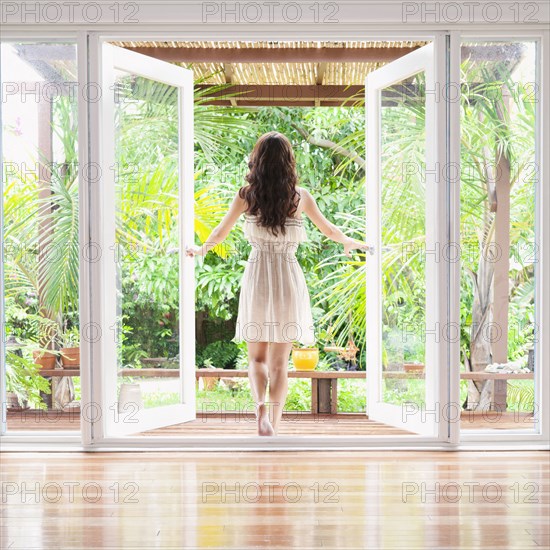 Hispanic woman opening French doors to patio