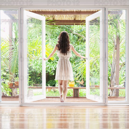 Hispanic woman opening French doors to patio