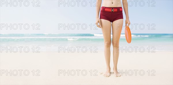 Caucasian woman holding plastic disc on beach