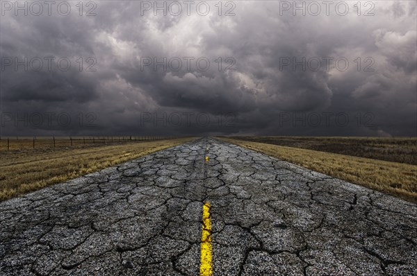 Cracked road under cloudy sky in remote landscape