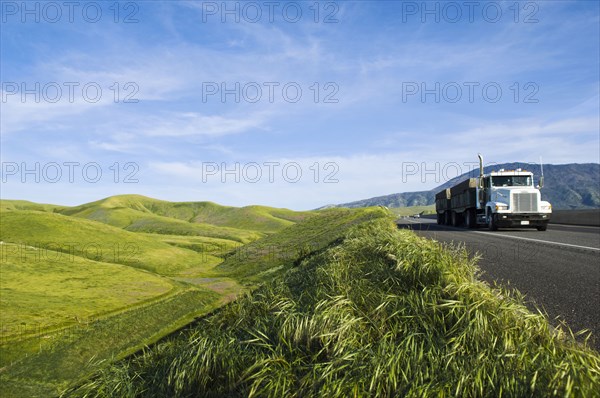 Truck driving on remote road in rolling landscape