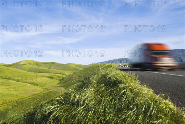 Truck driving on remote road in rolling landscape