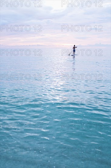 Caucasian man standing on paddleboard in ocean