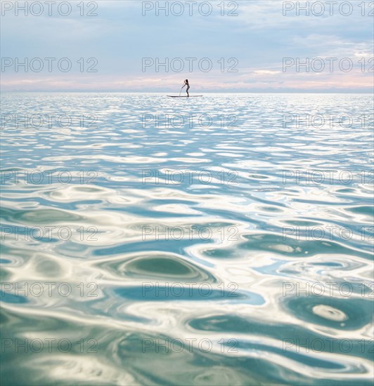 Mixed race woman standing on paddleboard in ocean