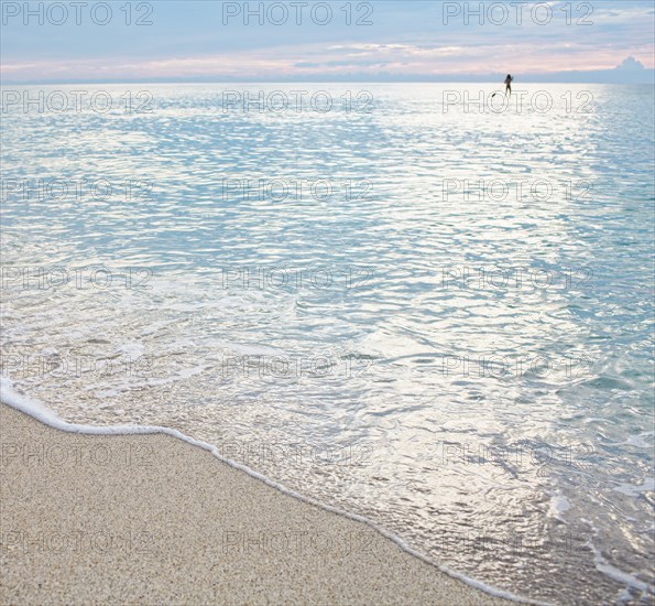 Mixed race woman standing on paddleboard in ocean