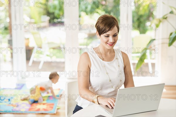 Caucasian mother using laptop at counter