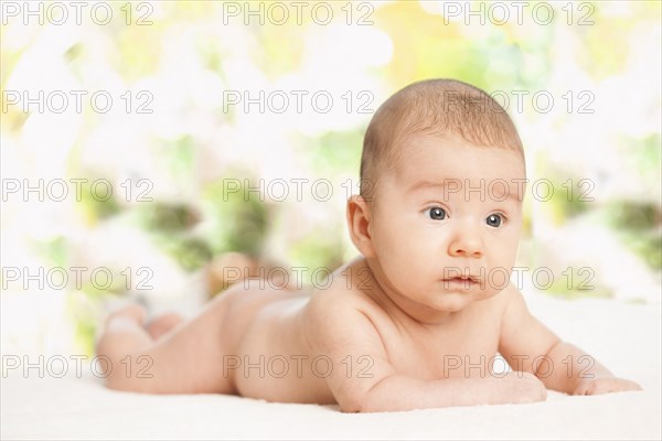 Nude mixed race baby laying on blanket