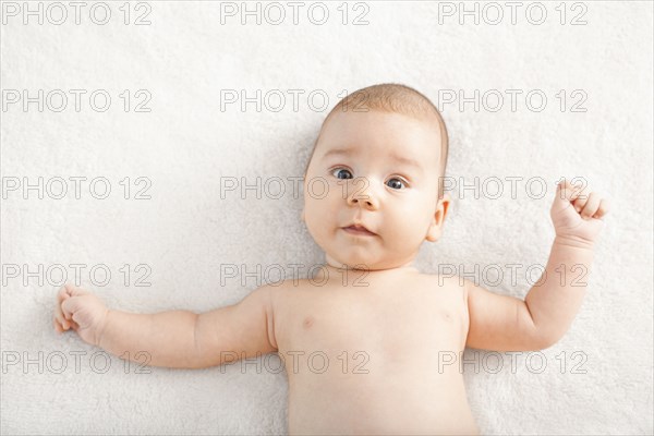 Nude mixed race baby laying on blanket