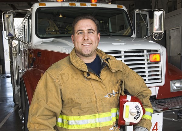 Caucasian firefighter smiling near fire truck