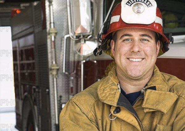 Caucasian firefighter smiling near fire truck