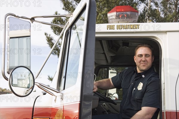Caucasian firefighter smiling in fire truck
