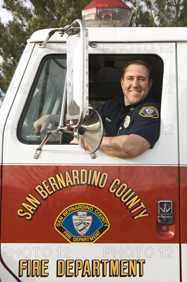 Caucasian firefighter smiling in fire truck