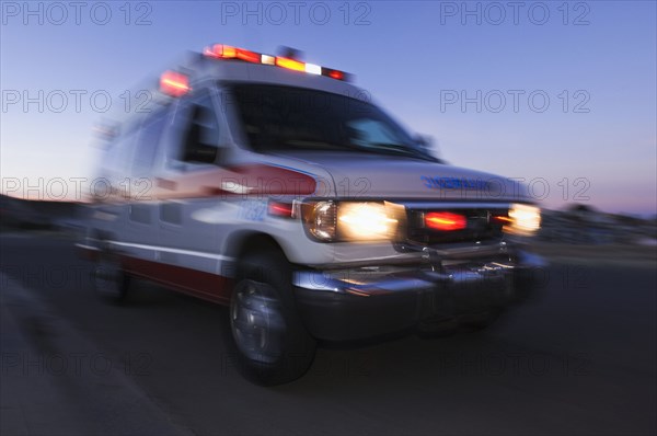 Blurred view of ambulance driving at dusk
