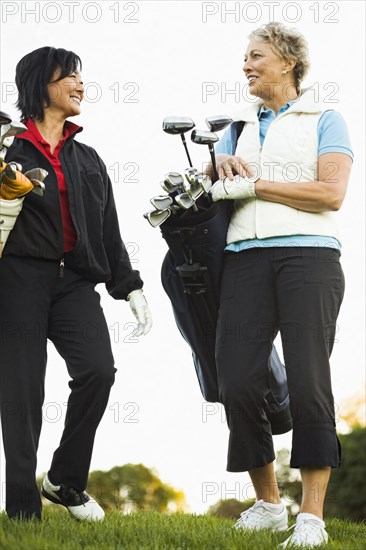 Women carrying golf clubs on golf course