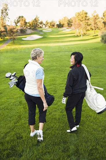 Women carrying golf clubs on golf course