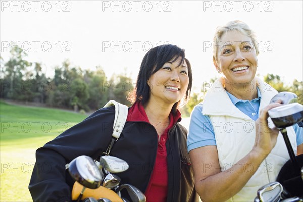 Women carrying golf clubs on golf course