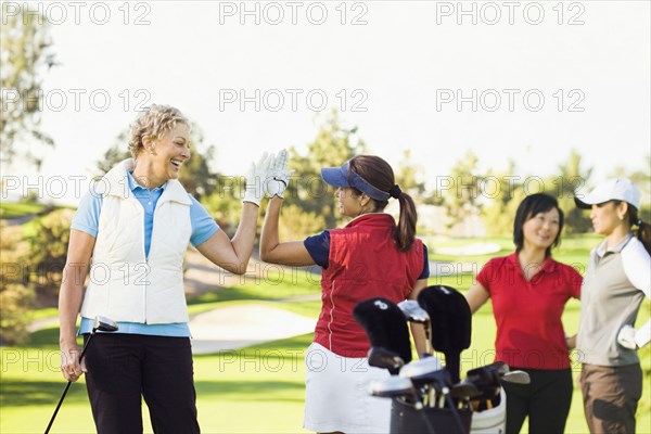 Women high-fiving on golf course