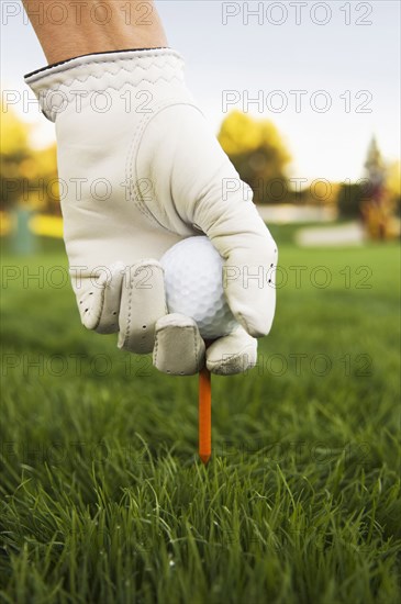 Mixed race woman placing ball on tee at golf course