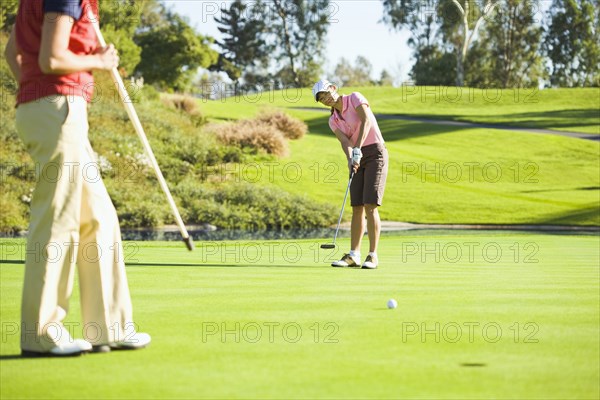 Women putting on green at golf course