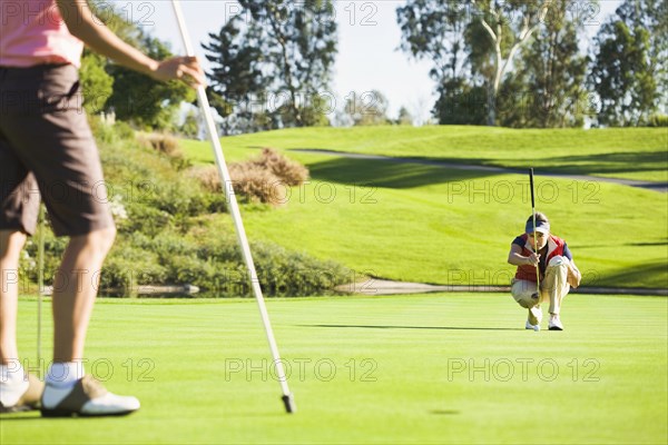 Women planning putt on green at golf course