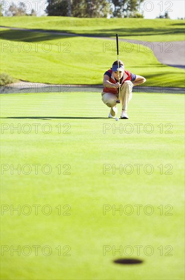 Caucasian woman planning putt on green at golf course