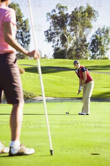 Women putting on green at golf course