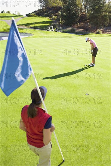 Women putting on green at golf course