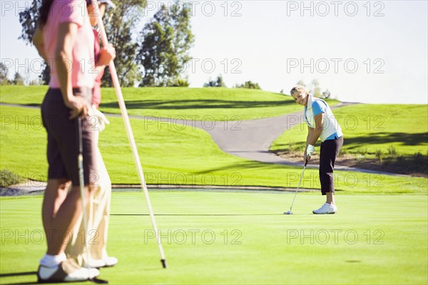 Women putting on green at golf course