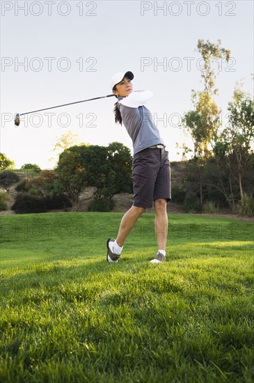Mixed race woman playing golf on golf course